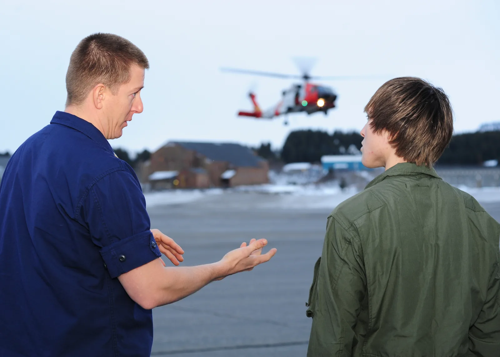 KODIAK, Alaska - Coast Guard Petty Officer 2nd Class Eric Stoecker, an aviation survival technician with Air Station Kodiak, explains search and rescue operations with Nando Macinko, a Kodiak High School student, at Air Station Kodiak Jan 26, 2011, while an MH-60 Jayhawk helicopter and crew provide a SAR demonstration.  During the job shadow day with the Coast Guard, Macinko expressed an interest in learning more about rescue swimmers as he is an avid swimmer in high school.  U.S. Coast Guard ph