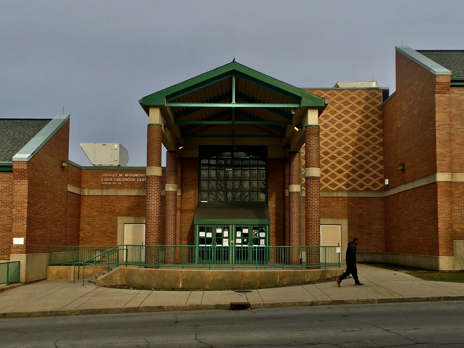 Buffalo Public School 99 aka the Stanley M. Makowski Early Childhood Center, 1095 Jefferson Avenue at Best Street, Buffalo, New York, April 2021. Built in 1994 by the local firm of Foit Albert on what was once the site of Gerhard Lang's Park Brewery, the building's architecture is emblematic of late Postmodernism in that the requisite Greco-Roman influences - here in the form of a pediment and colonnade framing the walkway leading to the main entrance - are joined by stylized nods to pre-Modern