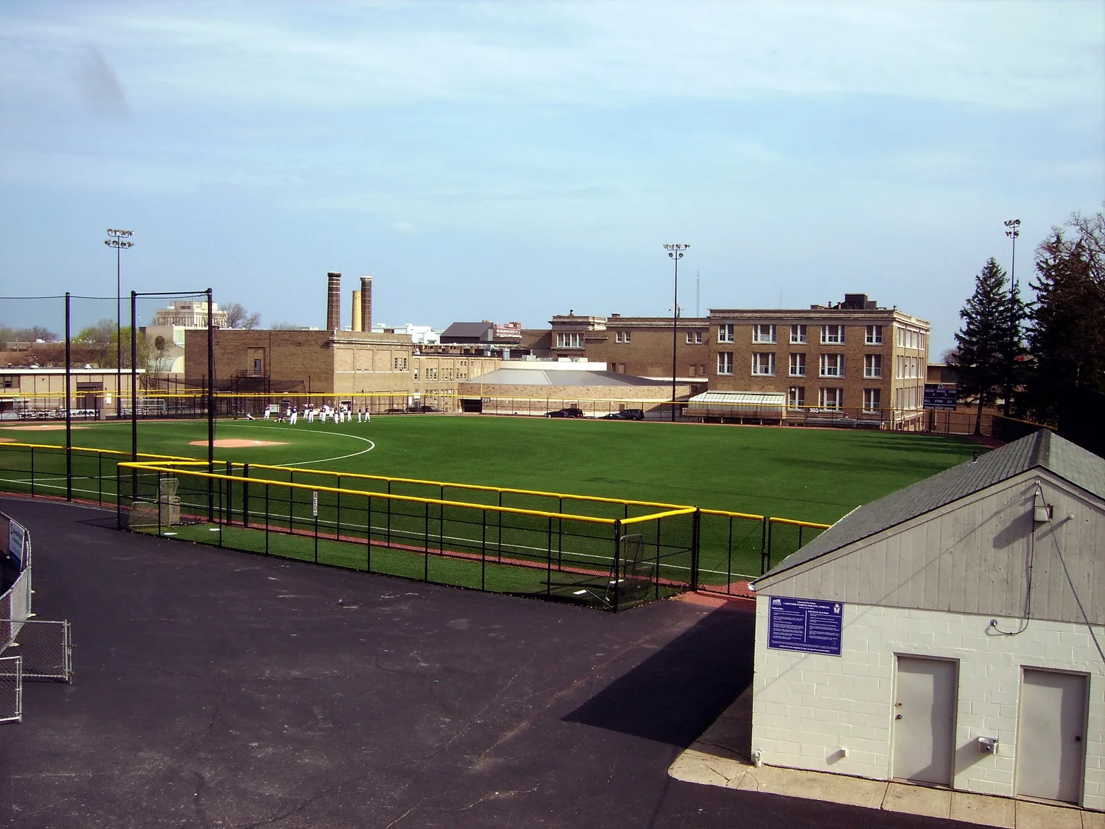 Lakewood High School, Lakewood, Ohio rear view from football stadium. Foreground, baseball field, from left, Auto mechanics, pool (Background), Arts building, Music room (semi-circular roof), Science building (with greenhouse).